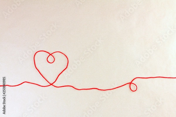 Fototapeta Red thread, heart and tangle on light craft paper background, top view