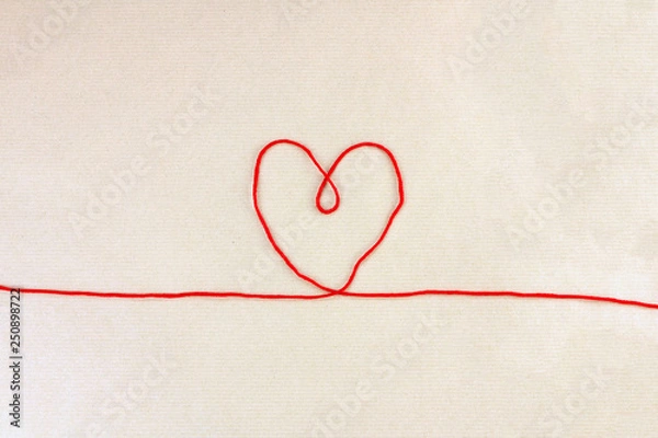 Fototapeta Red thread, heart and tangle on light craft paper background, love concept, top view