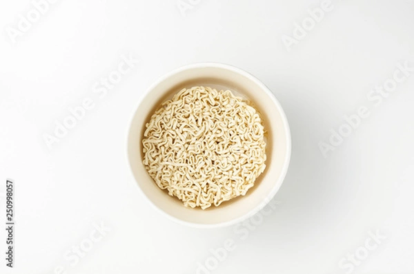 Fototapeta Overhead view of bowl with raw instant Asian egg noodles on white background