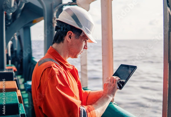 Fototapeta Marine chief officer or captain on deck of vessel or ship watching digital tablet. Internet and home connection at sea.