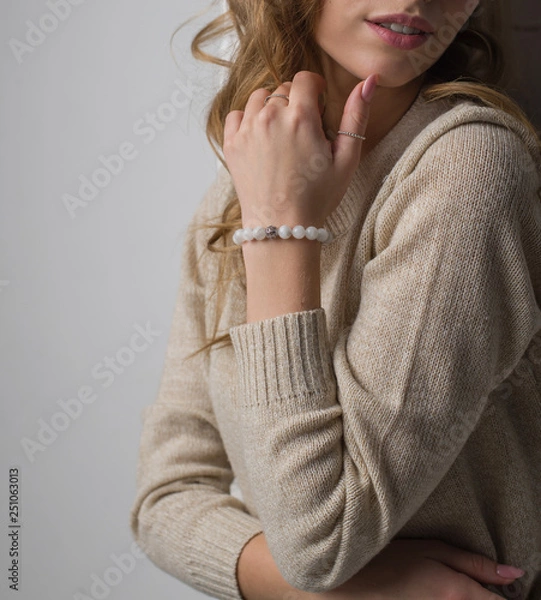 Obraz  bracelet made of moonstoneis on the hand, on the arm is a bracelet made of white stones, girl on white background