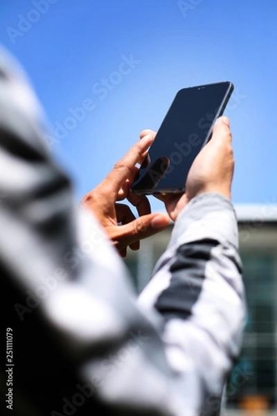 Fototapeta A man using smartphone in front of the office building.
