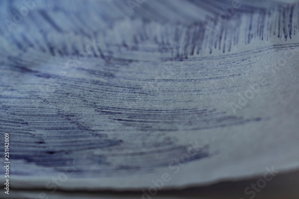 Fototapeta A sheet of white paper with painted dirty strokes, a blue ballpoint pen. Blurred background, shallow depth of field. Drawn record. Incomprehensible scribbles. The texture of an ordinary sheet of torn 