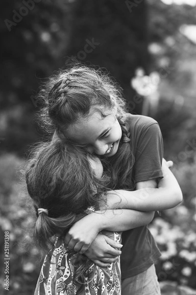 Obraz Black and white portrait of Two Happy little girls laughing and hugging at the  summer park.