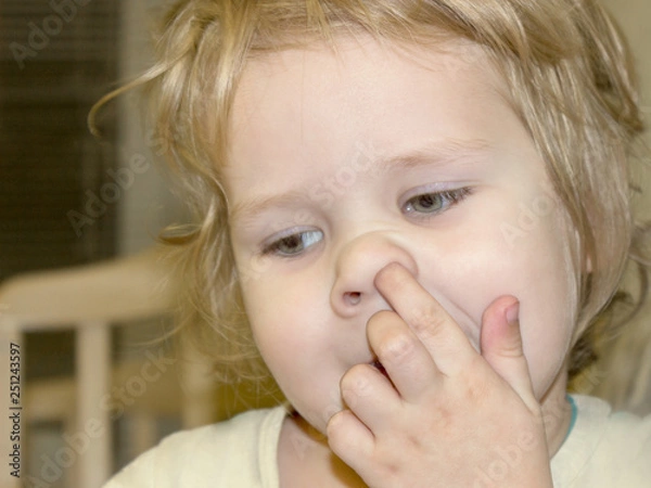 Obraz Little cute boy has a bad habit. The kid picks his nose and tries to get the dried-up salpi from the sinuses. What are the causes and ways of getting rid of the bad unpleasant habits of the child.