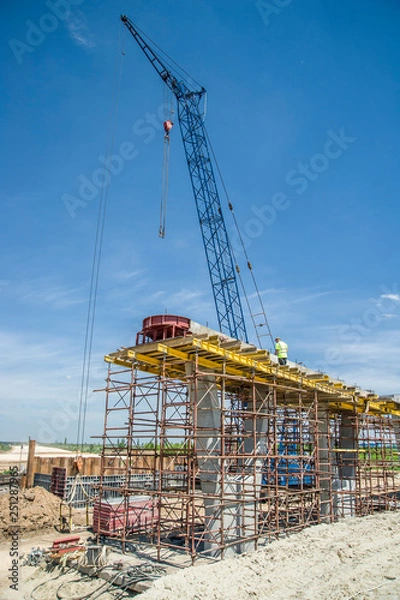 Fototapeta Hoisting crane at bridge support construction