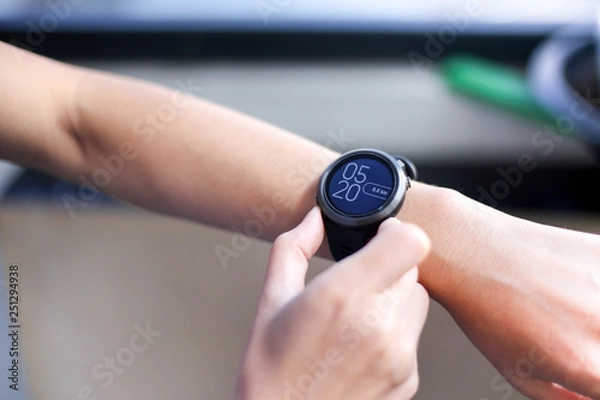 Fototapeta Use of fitness smart watch to monitor her performance.