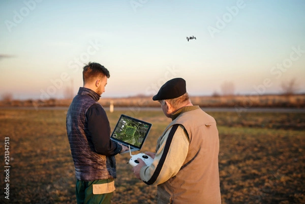 Fototapeta Technician farmer use wifi computer control agriculture drone on field 