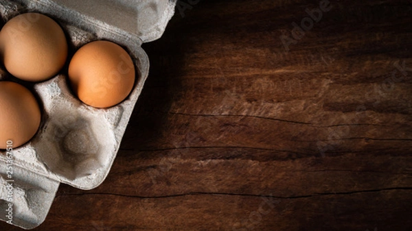 Fototapeta Fresh brown eggs in a carton box was placed on a wooden table to prepare food. Have copyspace to enter text. In aspect ratio 16: 9. Useful for health and easy to find according to the supermarket.
