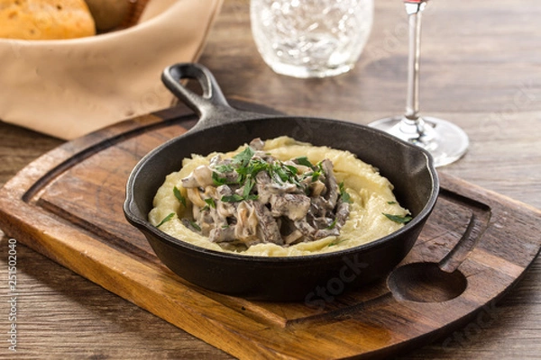 Fototapeta Beef stroganoff with mushrooms in frying pan on wooden table