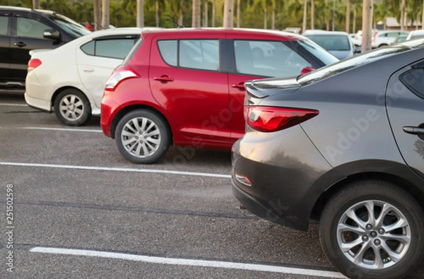 Fototapeta Closeup of back or rear side of brown car and other cars parking in parking area with natural background in twilight evening. 