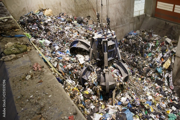 Obraz Mechanical claw hand grabbing pile of mixed waste