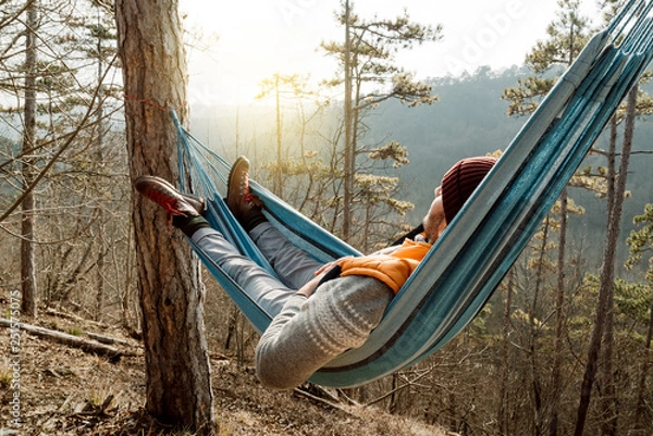 Obraz Young happy man relaxing lying in hammock on top of mountain.