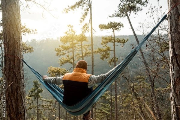 Obraz Young happy man relaxing lying in hammock on top of mountain.
