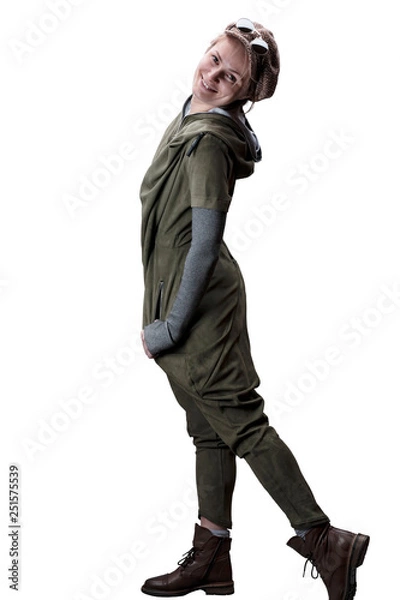 Fototapeta Young woman in a green jumpsuit in a cap and glasses posing in the studio isolated on a white background.