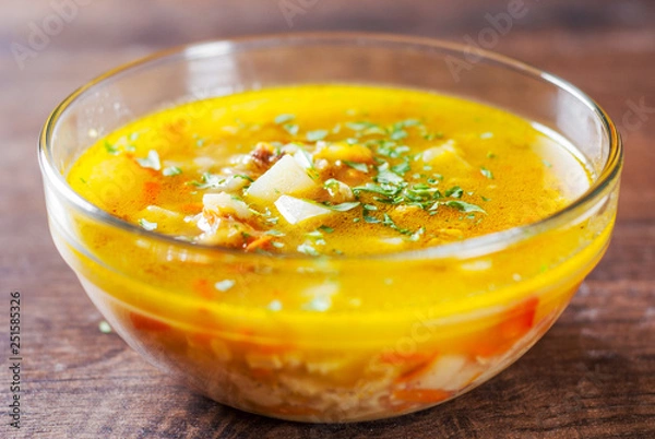 Fototapeta chicken soup with vegetables and rice in glass Bowl on wooden table background