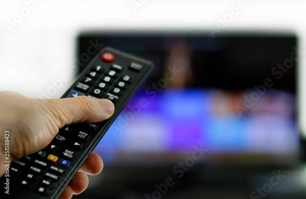 Obraz Hand holding remote control: Binge watching TV show