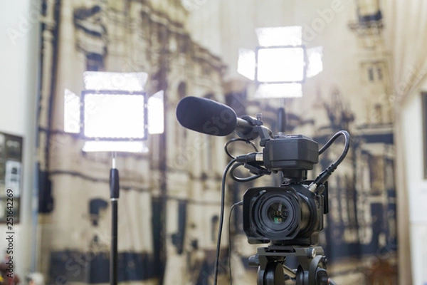 Fototapeta Shooting a report in the interior. Video equipment: camera, on-camera microphone gun, led lighting device, tripod.
