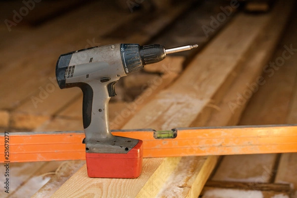 Obraz Cordless drilling tool using to build a wooden house. Construction tool close-up background.