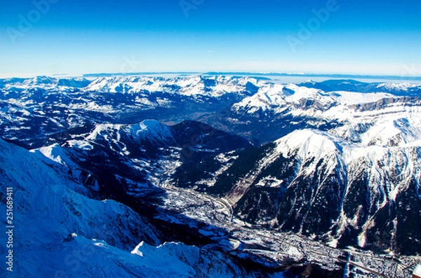 Fototapeta Panoramic view of mountains and french town called Chamonix-Mont-Blanc. All around the summits of Alps covered with snow.  Ideal destination for winter holiday full of skiing and snowboarding.