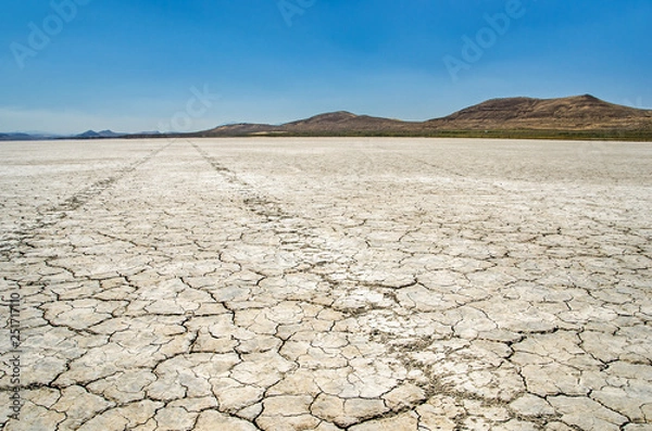 Obraz Vast desert floor with tire tracks leading into the distant mountains