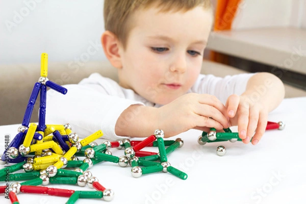 Fototapeta Cute little child boy playing magnets toy for brain development, fine motor skills and creativity concept