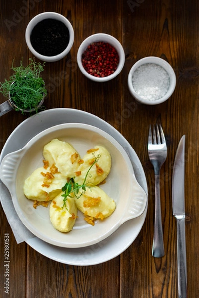 Fototapeta Mashed potatoes serving in a white plate on a wooden background, top view