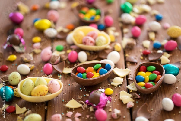 Fototapeta easter, sweets and confectionery concept - close up of chocolate eggs and candy drops on wooden table