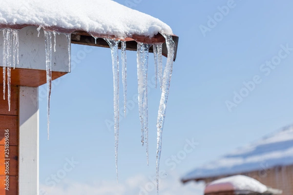 Fototapeta Icicle melts with falling drops on a background of bright blue sky