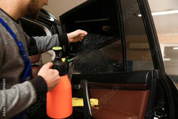 Fototapeta Worker tinting car window in shop, closeup