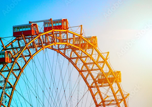 Fototapeta Ferris wheel in the rays of setting sun, blue sky backgroung. Vienna, Austria