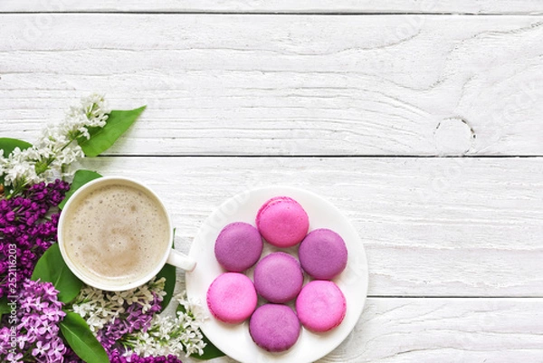 Fototapeta spring holiday background. flatlay with lilac flowers, macarons and cup of cappuccino on white wooden table