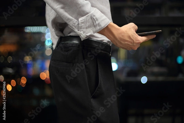Fototapeta businessman checking on mobile phone in a modern office with out of focus lights in the background. office worker night at the office. modern businessman concepts.