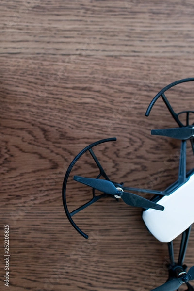 Fototapeta Small black and white drone on a wooden table. toy drone for activities with children and teenagers. Wooden background with a drone