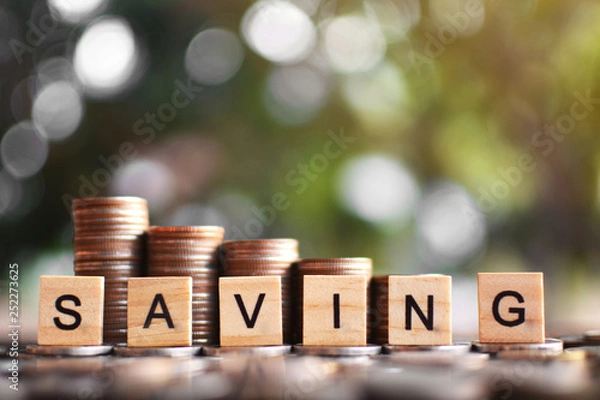 Fototapeta Coins set arranged vertically on wood plank and tree bokeh background , Saving and growing business concept, selective and soft focus.