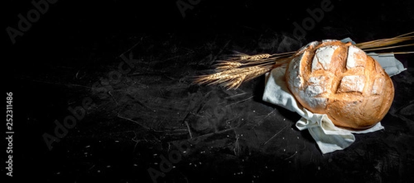Fototapeta Rustic bread of whole wheat grains on dark background with copy place