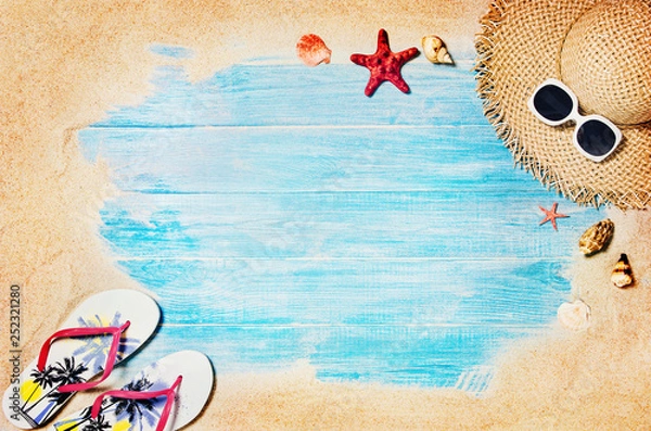 Fototapeta Top view of sandy beach with blue marine planks frame and summer accessories. Background with copy space and visible sand and wood texture. Border composition