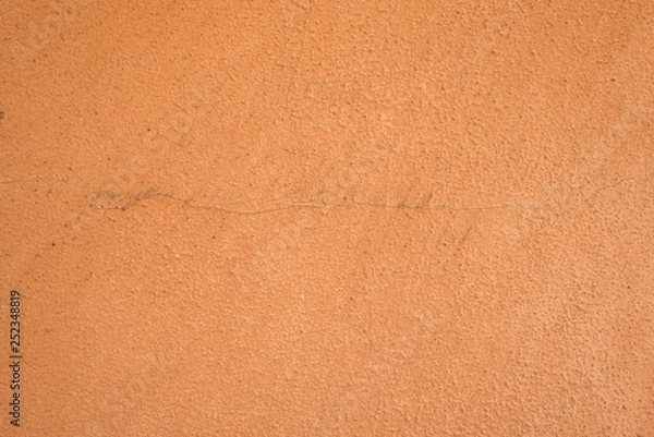 Fototapeta Terracotta, burnt sienna colored wall of house or building with scratch coat plaster work painted in orange peach color with rough texture, already some years old with cracks, filthy and dirty