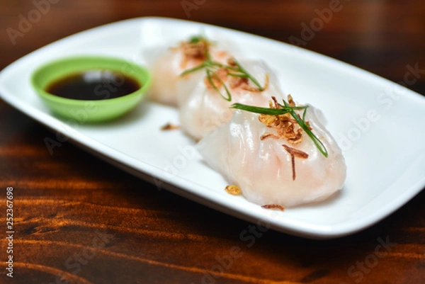 Fototapeta Traditional asian rice dough steamed dumplings with stuffing, spring onion and fried chips decor, served with spicy chilly sauces