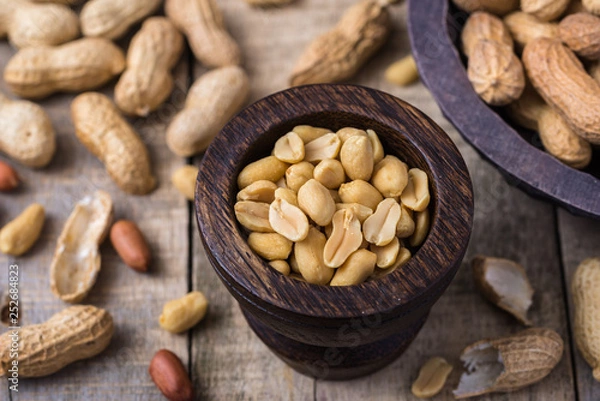 Obraz Peanuts in small dark wooden bowl on natural rustic desk.