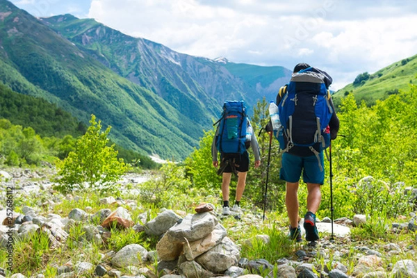 Fototapeta Friends walks in mountains. Journey in Alps mountain trail. Tourists on mountain trek