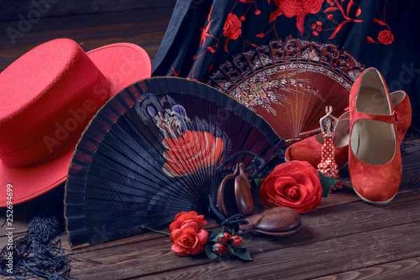 Fototapeta Beautiful and bright accessories for flamenco dance and souvenirs on a wooden background in a low key. Shawl, hat, fan, shoes, castanets