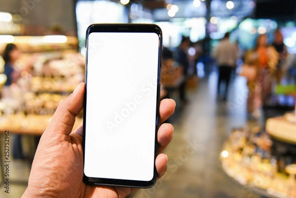 Fototapeta Man holding smart phone with bank moblie can be add your texts or others. at bakery shop