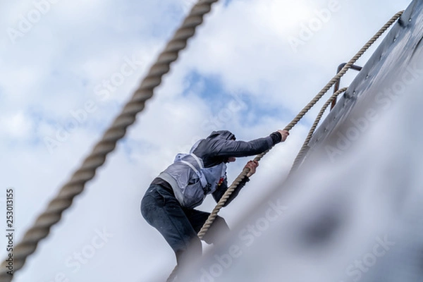 Fototapeta A man climbs an obstacle at a sporting event