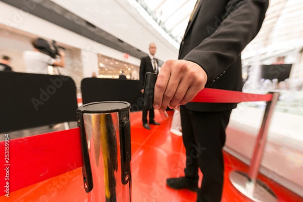 Fototapeta Security hand fastens a red tape closing the passage