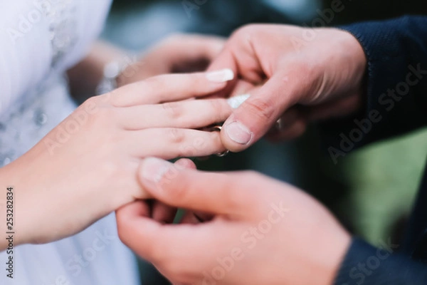 Fototapeta Hands of groom and bride with rings. wedding dress, wedding details 