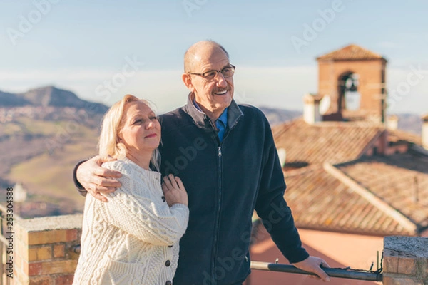 Obraz Hugging senior couple in vacation, visiting old Italian town.