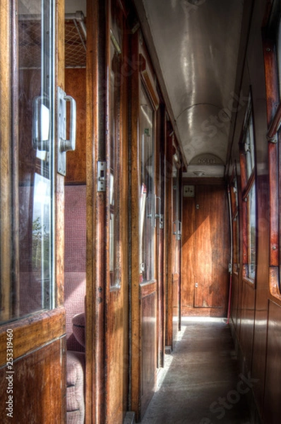 Fototapeta Interior shot of vintage railway carriage corridor showing wooden fittings, windows to one side and compartments to the other.
