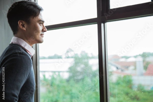 Obraz portrait of asian young man look out to the windows in the office
