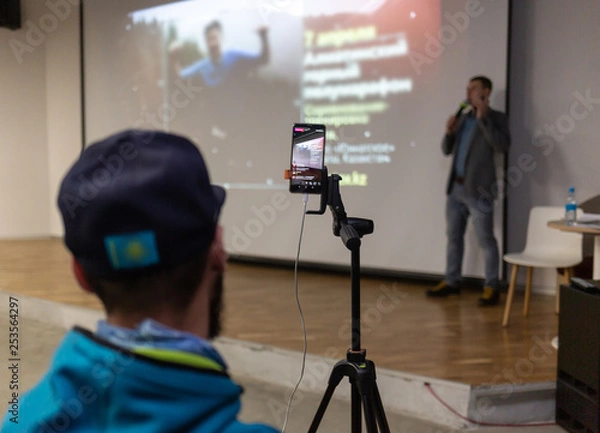 Fototapeta A man with a tripod shoots a live stream on Instagram